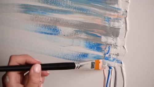 Une jeune artiste dessine une image abstraite, couleurs pastel, peinture acrylique