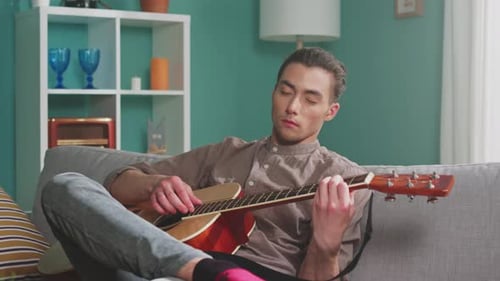 Young Adult Playing Acoustic Guitar Indoors