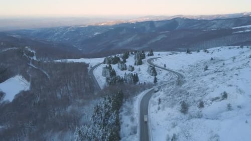 White Transportation Trucks Driving Trough Frozen Mountain on Asphalt Mountain Highway