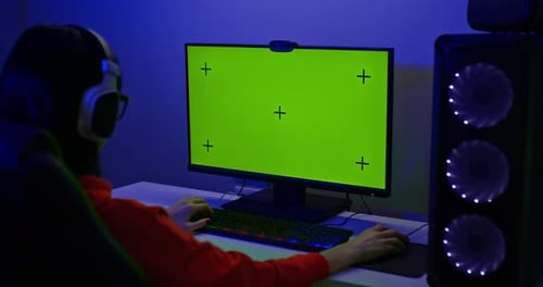 Greenscreen eines leistungsstarken PCs Eine Spielerin sitzt an einem Computer