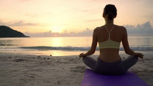 Woman Meditating on Beach at Sunset