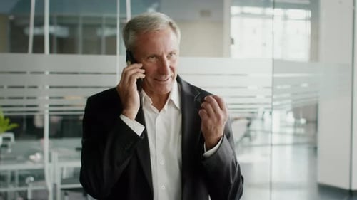 Mature Businessman Talking On Mobile Phone Standing In Modern Office