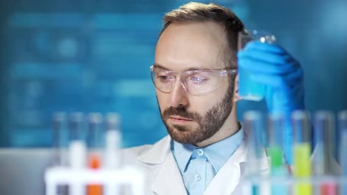 Focused Scientist Examining Blue Liquid in Beaker