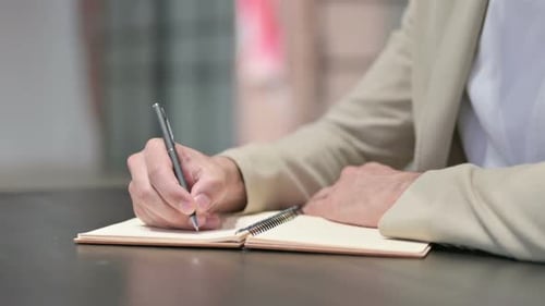 Close Up of Young Man Writing on Notebook
