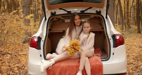 Mother and Child in Car Trunk in Fall Forest