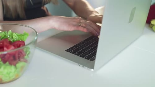 Female Hands Typing on Keyboard of Laptop on Kitchen Table