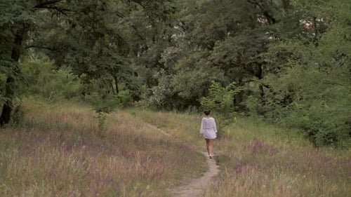 Young Woman Walking Through Lush, Green Meadow
