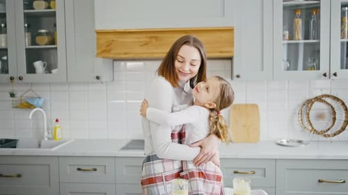 Happy Woman and Girl Embrace in Kitchen