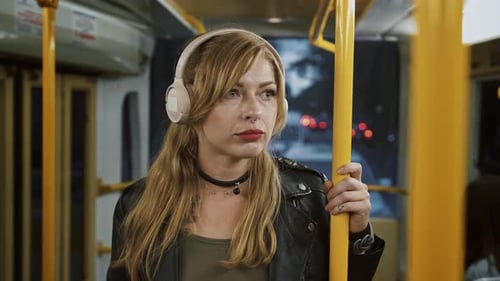 Woman Listening to Music on Public Transportation at Night