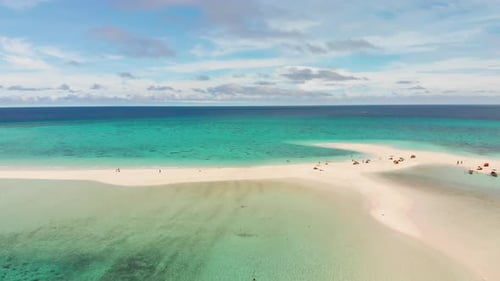 tourist enjoying their relaxing vacation on a tropical white sandy beach surrounded by blue turquois