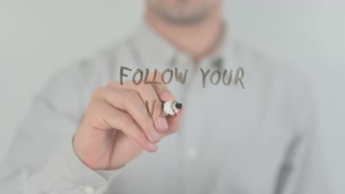Man Writing 'Follow Your Vision' on Clear Surface