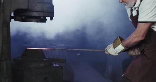 Senior Man Shaping Metal in an Industrial Workplace
