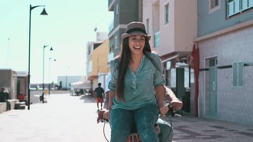 Interracial couple have fun together riding a bike in outdoor in the city - happiness and joy young