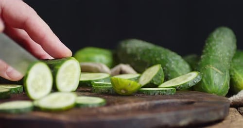 Slicing Fresh Cucumbers on Wooden Cutting Board