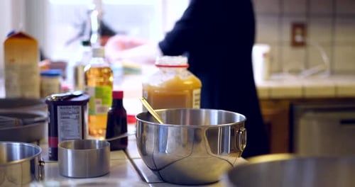 A woman chef cleaning up and rinsing dishes as she is baking a vegan chocolate cake recipe on a mess