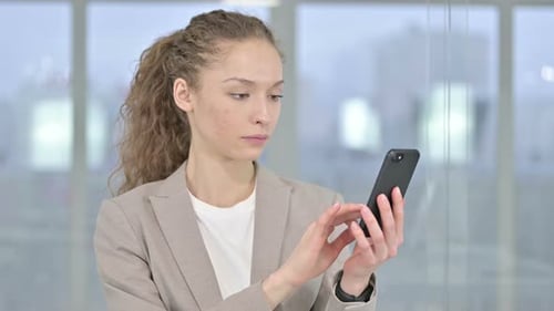 Woman Using Smartphone in Modern Office Setting