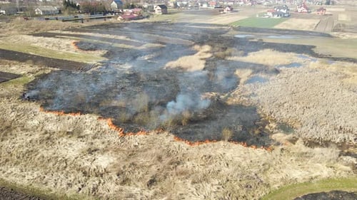 Aerial View of Firemen Extinguishing Grassland Field Burning with Red Fire During Dry Season