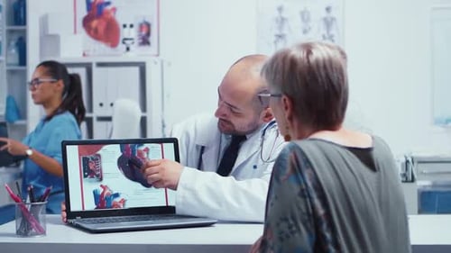 Doctor Consults with Senior Woman, Shows Heart Diagram