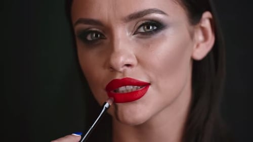 Woman Applying Red Lipstick with Brush, Close Up