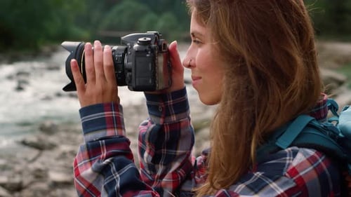 Woman Taking Pictures Near a Mountain Stream