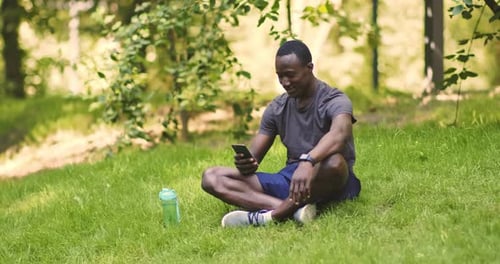Millennial African American Man Browsing on Smartphone in Park