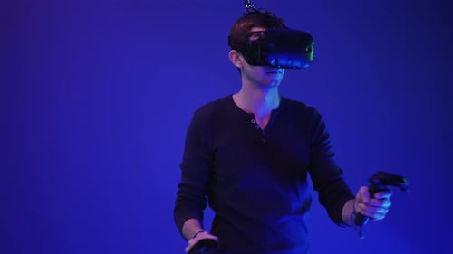 Young Adult Using Virtual Reality Headset and Controllers
