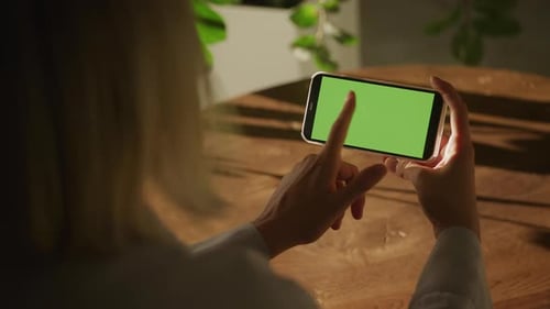 Handheld Close Up of Caucasian Woman Holding Smart Phone with Green Screen and Swiping Left