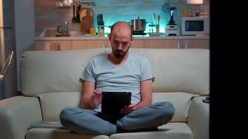 Man Sitting on Couch Using Tablet