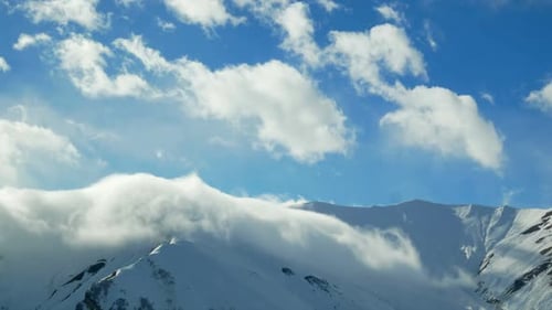 Snowy Mountains Under a Blue Sky with Clouds