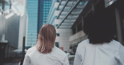 Two young women in business attire walk away with a bike in a business area