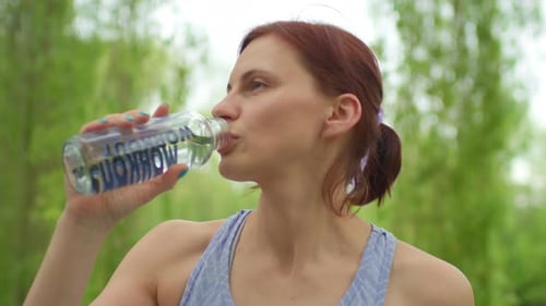 Close Up of 30s Woman Drinking Water Holding Bottle in Hands