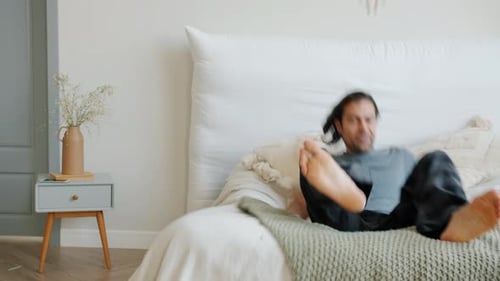 Man Jumps Onto Bed To Relax In Bedroom