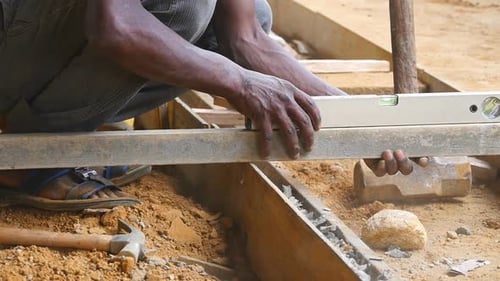 Un homme indien vérifie les niveaux de précision lors de la construction d'un plancher en bois. Local méconnaissable