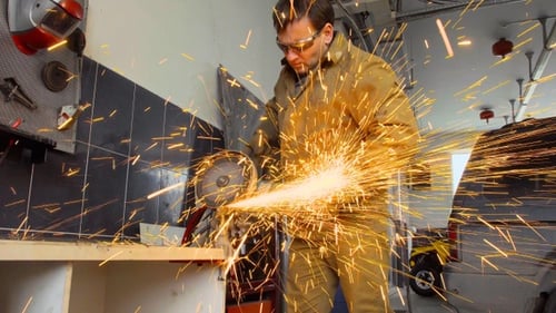 Worker using a grinder cuts metal in a workshop