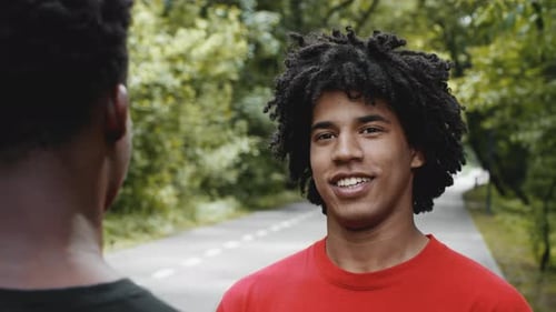 Zwei afroamerikanische Millennial-Männer sprechen im Park im Freien