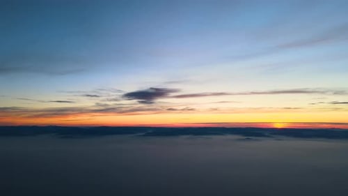 Vue aérienne du coucher de soleil coloré sur une couverture de nuages brumeux denses et blancs avec de lointaines silhouettes sombres de