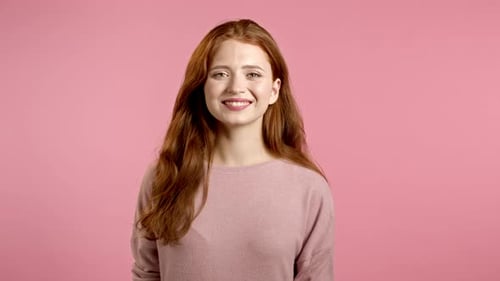 Young Smiling Woman with Red Hairstyle Looking To Camera. Portrait of Cute Beautiful Girl on Pink