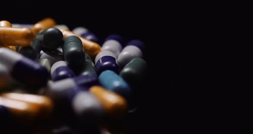 Assorted Medicine Capsules on Reflective Black Surface