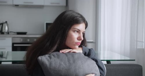 Young Woman Resting with Pillow on Couch Indoors