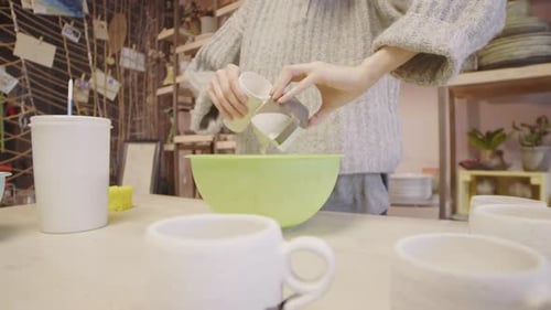 Handwerkerin malt Keramikbecher in Werkstatt
