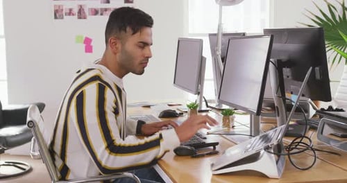Mann gemischter Abstammung arbeitet mit Computer im kreativen Büro
