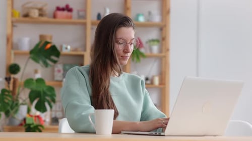 Woman Works on Laptop at Home Desk
