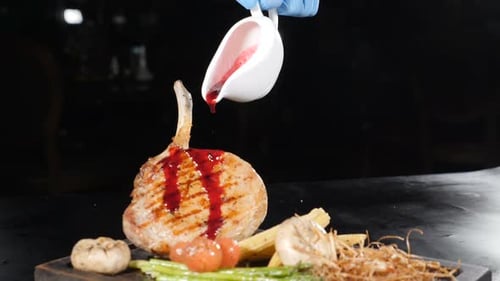 Pouring Red Sauce Over a Grilled Meat Chop