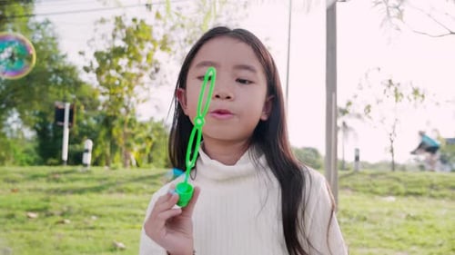 Girl Blowing Bubbles in a Suburban Park