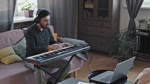 Man Playing Digital Piano at Home with Headphones
