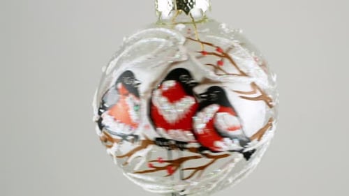 Christmas tree toy ball with transparent patterned snigheri slowly rotates on a white background.
