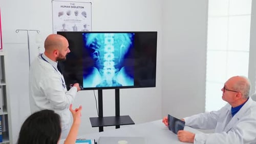 Medical Professionals Discussing Spine X-Ray in Office