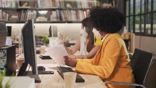 Young people with face masks back at work in office after lockdown