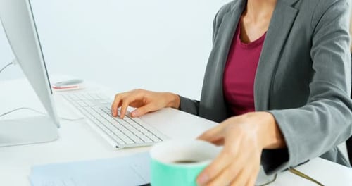Femme d'affaires prenant un café tout en travaillant au bureau