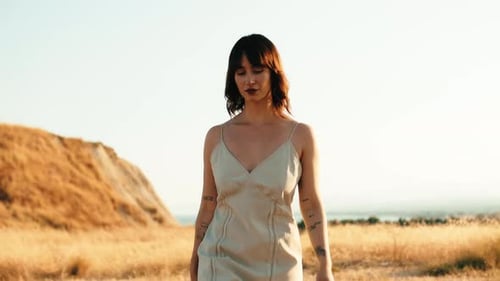 Young Girl in White Dress Walks in a Yellow Field